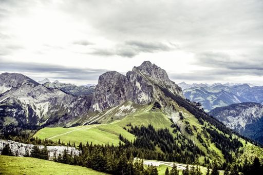 An aerial view of green rocky mountains under the beautiful cloudy sky