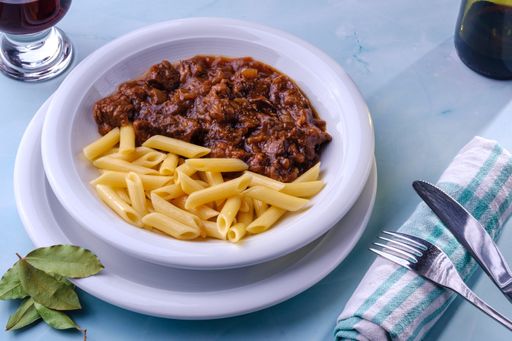 A plate with juicy beef goulash and penne pasta