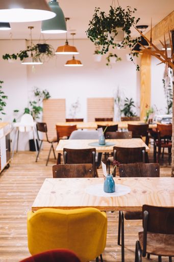 The interior of the empty restaurant with wooden chairs, tables and different plants