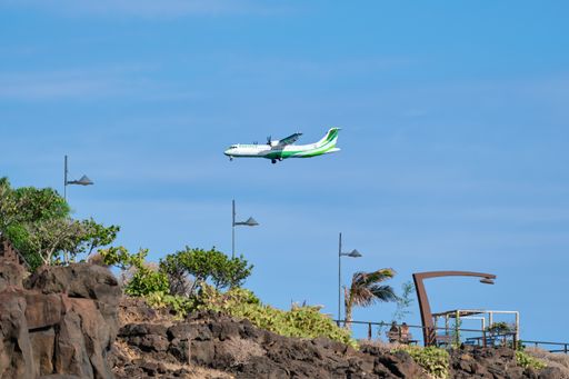 A turboprop airplane approaching El Hierro with a volcanic coast and a promenade with palm trees. Vacation on the Canary Islands. ATR 72 flight.