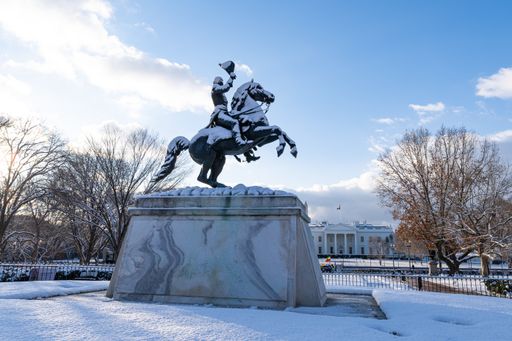 The equestrian statue of Andrew Jackson in Lafayette Park covered in snow with the White House in the background.