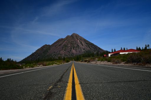 A view of a long road going to the beautiful mountain under the blue sky