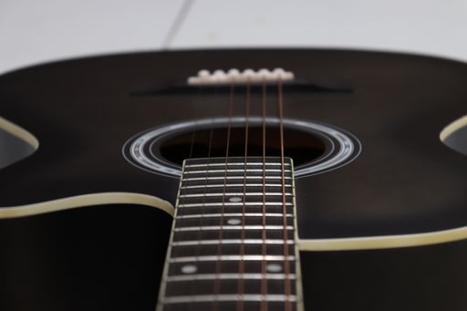 A closeup shot of details on a dark brown acoustic guitar