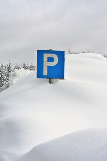 A vertical shot of a blue parking sign covered in snow