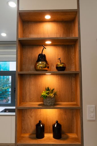 A vertical shot of a wooden cupboard with illuminated shelves and decorations