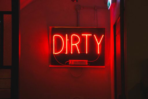 A closeup shot of a red neon light sign  with the text [dirty]