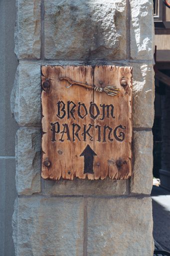 A vertical closeup shot of a sign [broom parking] in Diagon Alley, Harry Potter world