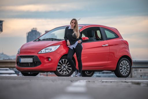 A young white Caucasian girl enjoying driving her little red car