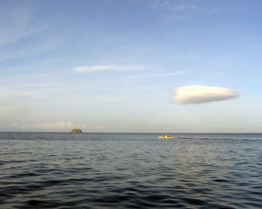 A wide shot of a small inflatable boat on the body of water under a blue sky
