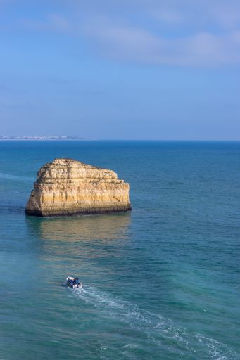 A scenic rock in the open blue sea near Benagil during the sunset, Portugal - December 30, 2021