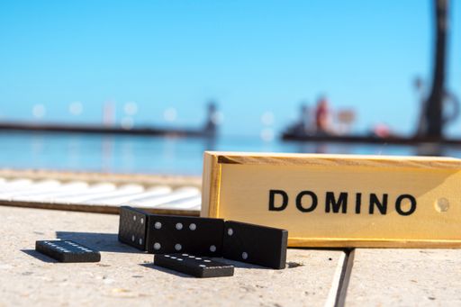 A closeup shot of a wooden domino box and dominoes on a water background