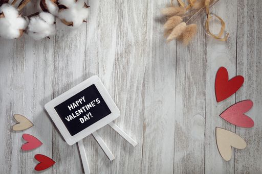 A top view of a tablet with the text "Happy Valentine's Day" and decorations on a wooden background
