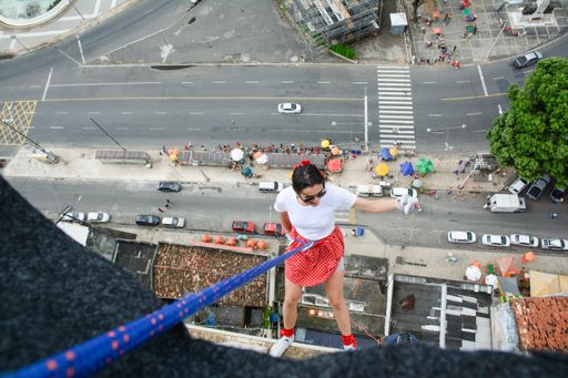 A caucasian woman wearing a hero costume descending from a tall building in Salvador, Brazil