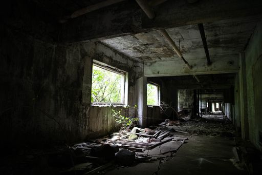 An empty and dark hallway with rubbles and concrete walls in an abandoned building