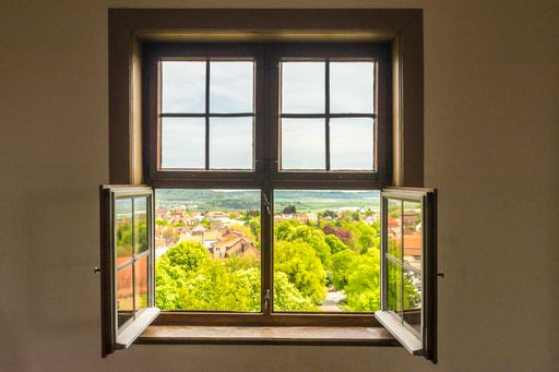A beautiful view through the open window to the city and green gardens
