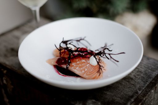 A high angle closeup shot of a luxurious dish with fish and sauce on a white plate