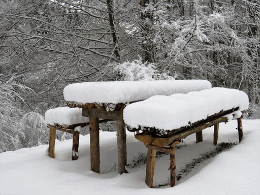A snowcovered wooden bench and table in a park