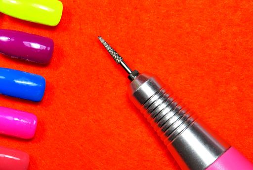 A high angle shot of nail cutter with colorful nails on a red surface