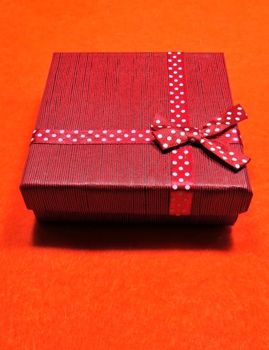 A vertical closeup shot of a red gift box on an orange surface