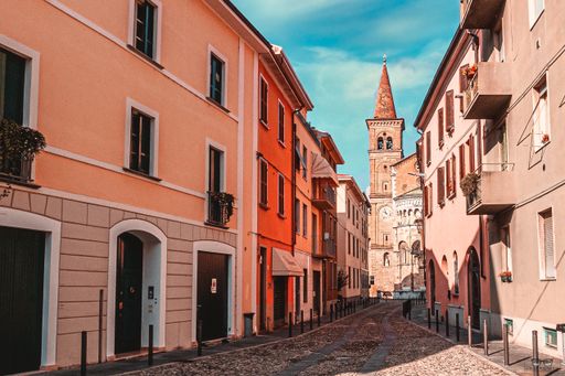 An empty narrow street surrounded by colorful buildings under a blue sky