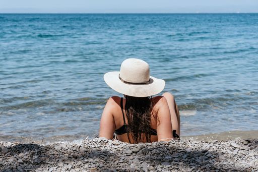 A back view of a young Caucasian woman relaxing on the beach in Moon bay, Slovenia