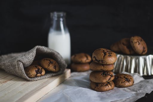 A selective closeup shot of baked chocolate cookies near a bottle of milk