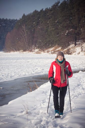 A vertical shot of active woman hiking with poles in Neris Regional Park, Lithuania during winter