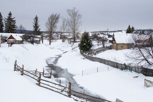 A beautiful view of a snowfall in the village against the background of mountains