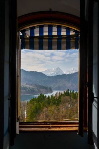 A vertical shot of a fantastic scene of the Alps, crystal lake and trees opening from a window