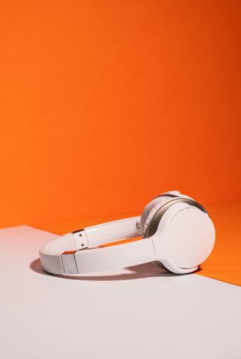 A White wireless headphones on an orange and white background