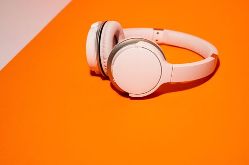 A White wireless headphones on an orange and white background