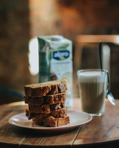 A selective focus shot of delicious bread cake with a glass of chocolate milk on a table