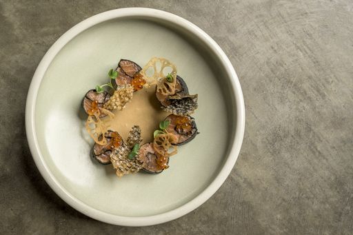 A high angle shot of fusion food with sushi and seasonings in a plate on a wooden surface