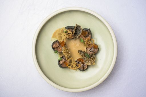 A high angle shot of Asian food with sushi and seasonings in a plate on a white surface