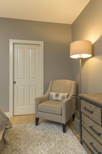 A vertical shot of a chair and a lamp with a white door