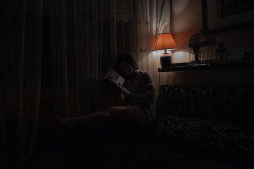 A woman reading a book in the dark room