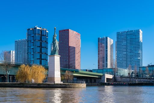 A scenic view of the Grenelle bridge on the Seine with the liberty statue against the buildings