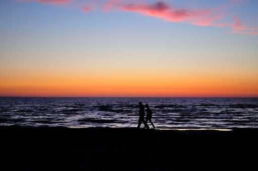 A silhouette of tourists walking on the shore at a beautiful sunset