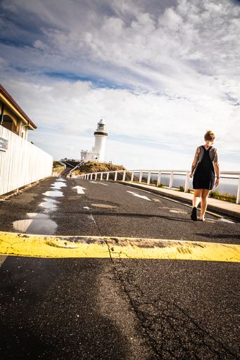 A back view of human walking on street in front of the lighthouse in sunny day