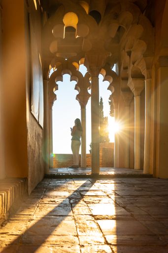 A tourist hunched over a column of the Arab doors of a courtyard of the Alcazaba in the city of Malaga