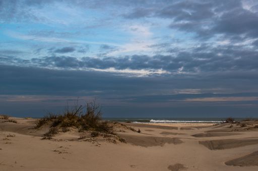 The sandy coast with cloudy sky on the background