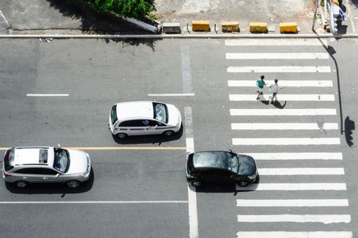 The three cars stopped and two people crossed at the crosswalk.