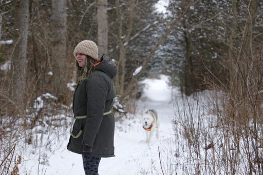 A Caucasian woman with her Alaskan malamute playing in the snow