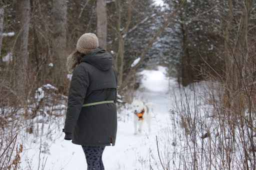 A Caucasian woman out in a snowy forest with her husky