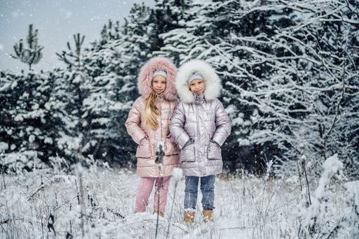 A Caucasian little girls having fun in a beautiful magic winter park during snowfall