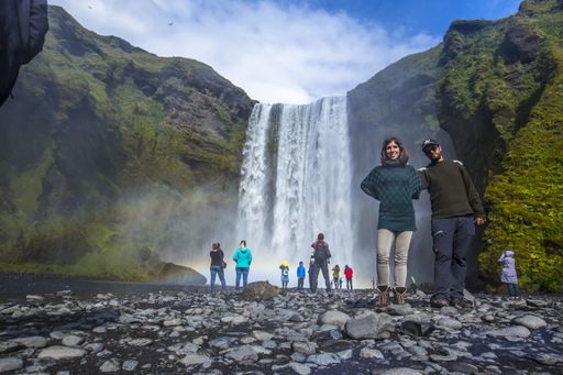 A lovely couple admiring the beauty of the Skogafoss waterfall in Iceland