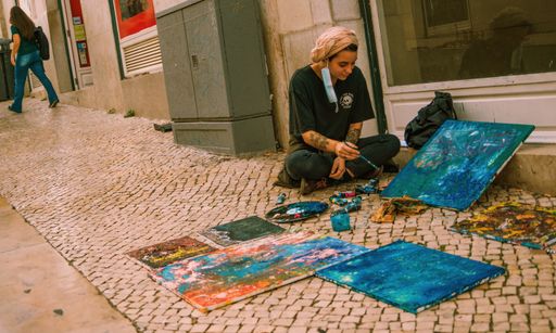 Lisboa, Portugal, October 28, 2021: A young street artist painting sitting on a sidewalk