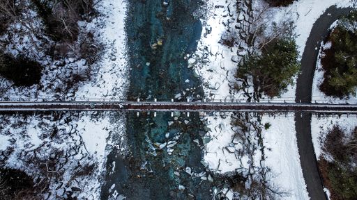 An aerial view of a beautiful bridge in Switzerland over clear river in winter
