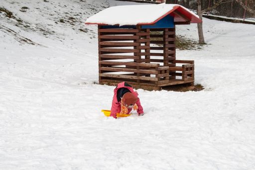 A child playing in the snow during the day in winter