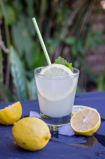 A vertical shot of a glass of refreshing cold lemonade on a table with lemons